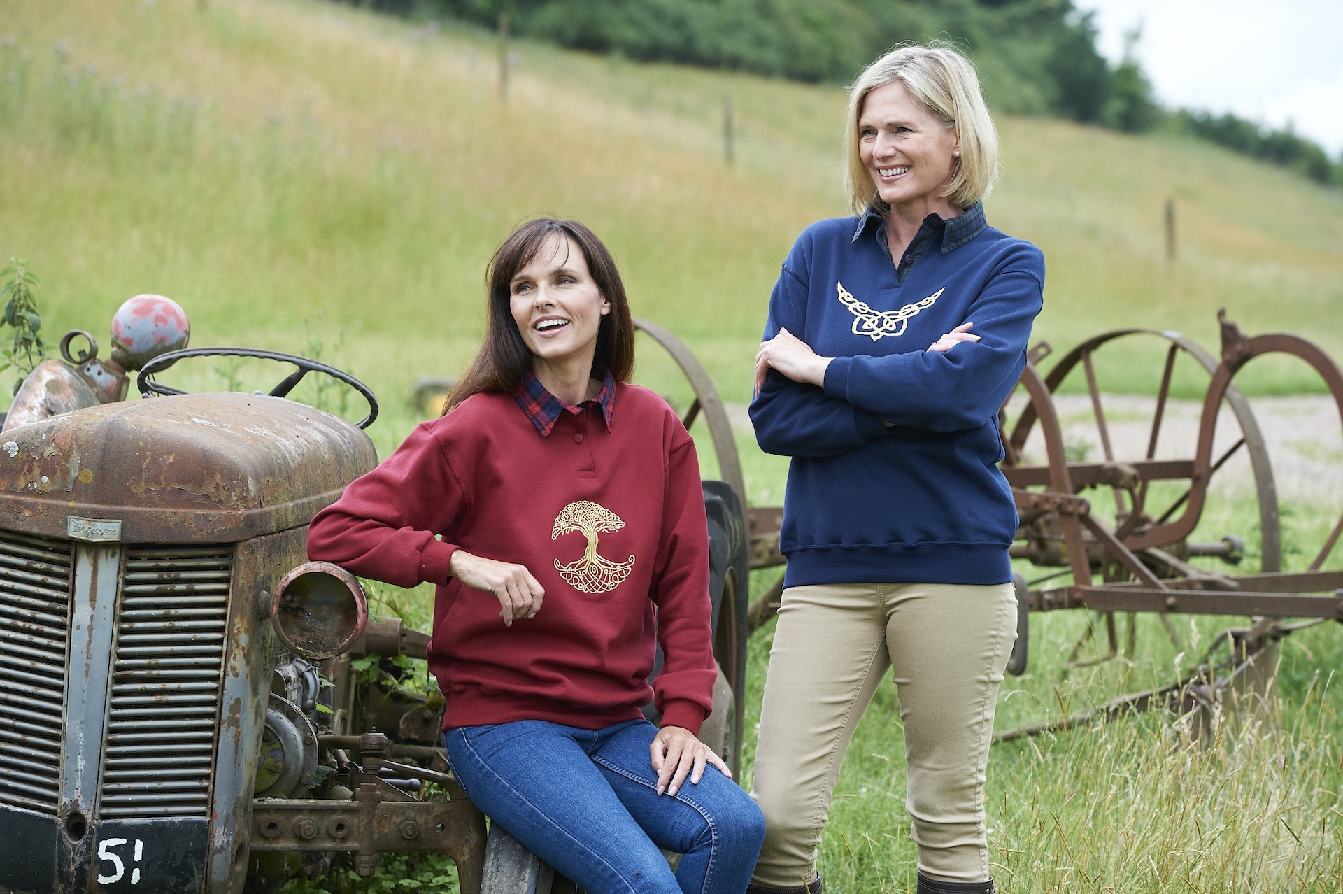 Two ladies by a rusty tractor wearing country clothing