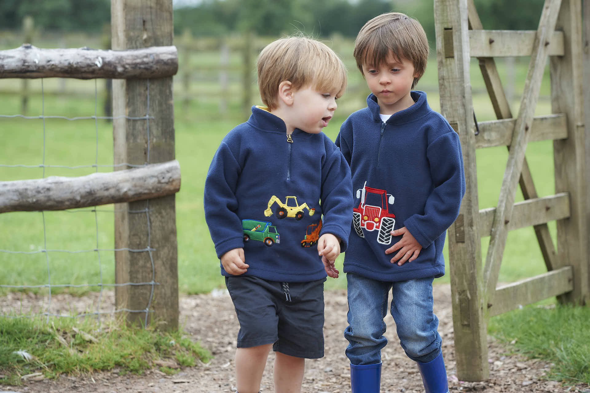 two young boys wearing navy blue fleeces featuring tractor designs